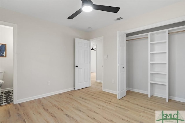 unfurnished bedroom featuring connected bathroom, baseboards, visible vents, and wood finished floors