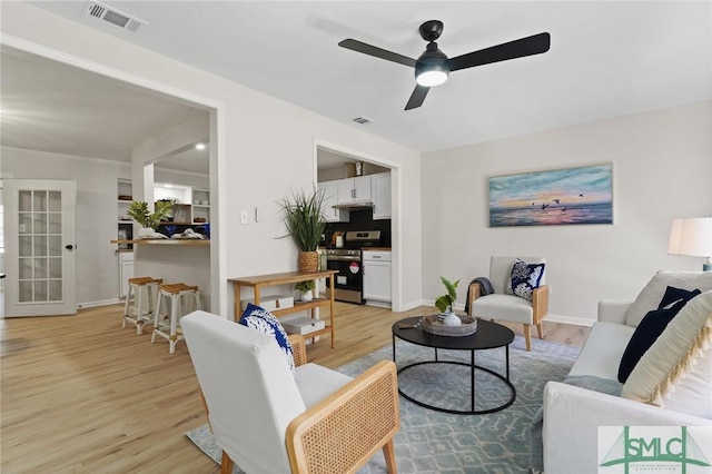 living room featuring baseboards, ceiling fan, visible vents, and light wood-type flooring