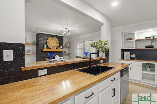 kitchen with butcher block countertops, dishwasher, ornamental molding, a sink, and open shelves