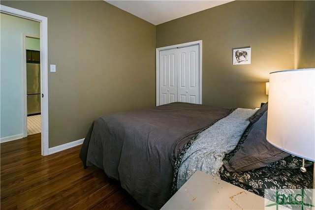 bedroom with baseboards, stainless steel fridge, wood finished floors, and a closet