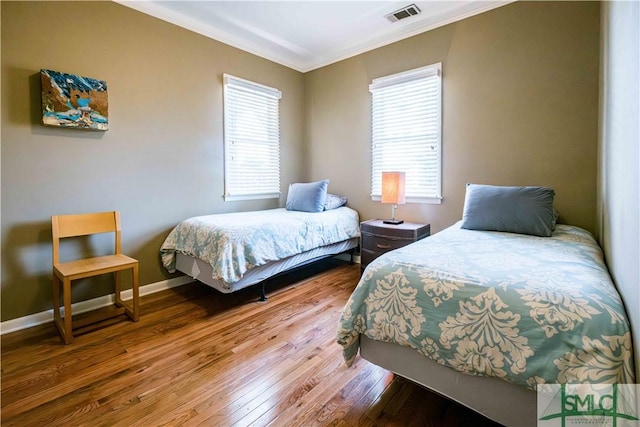 bedroom featuring visible vents, multiple windows, crown molding, and wood finished floors