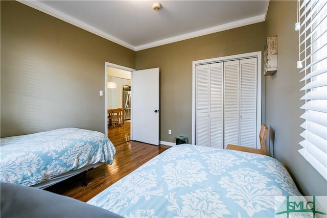 bedroom with baseboards, a closet, wood finished floors, and ornamental molding