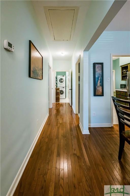 hallway featuring baseboards, dark wood-style floors, and attic access