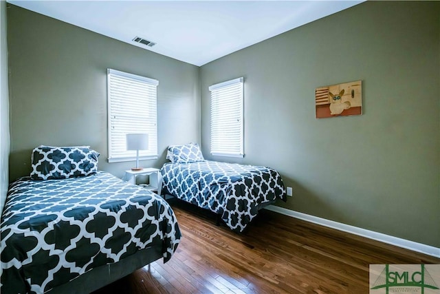 bedroom with baseboards, visible vents, and wood finished floors