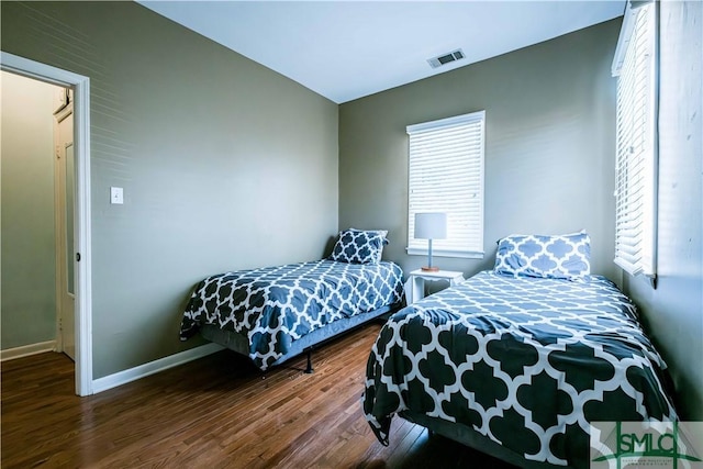bedroom featuring wood finished floors, baseboards, and visible vents