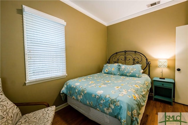 bedroom featuring baseboards, ornamental molding, visible vents, and wood finished floors