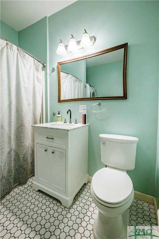 full bath with toilet, vanity, and baseboards