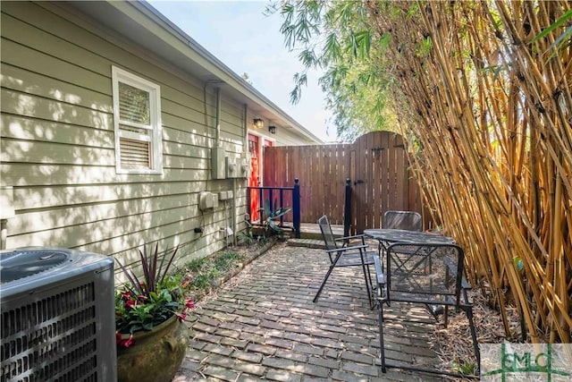 view of patio / terrace with a gate, fence, cooling unit, and outdoor dining area