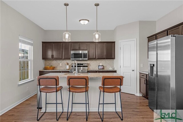 218 Herty Ln, Hinesville, GA 31313 - kitchen with stainless steel appliances, dark brown cabinets, tasteful backsplash, and a center island with sink