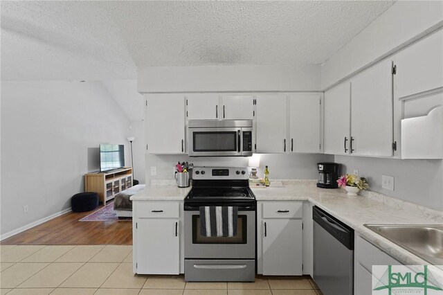 726 Timber Ridge Trl, Hinesville, GA 31313 - kitchen with light countertops, light tile patterned floors, stainless steel appliances, a textured ceiling, and white cabinets