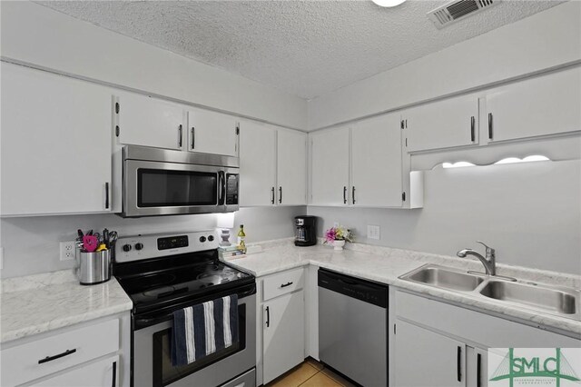726 Timber Ridge Trl, Hinesville, GA 31313 - kitchen with a textured ceiling, visible vents, white cabinets, stainless steel appliances, and a sink