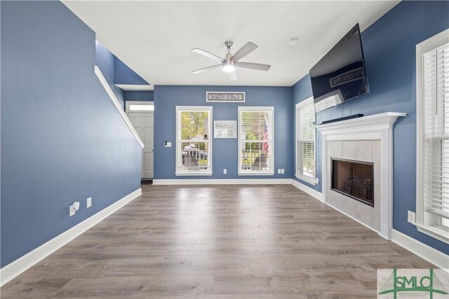90 Cottage Ct, Richmond Hill, GA 31324 - unfurnished living room featuring baseboards, a fireplace, wood finished floors, and a ceiling fan