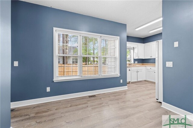 90 Cottage Ct, Richmond Hill, GA 31324 - kitchen featuring visible vents, light wood-style flooring, white appliances, baseboards, and white cabinetry