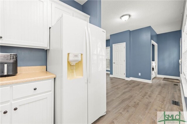 90 Cottage Ct, Richmond Hill, GA 31324 - kitchen with light wood-style floors, white cabinets, white refrigerator with ice dispenser, and light countertops