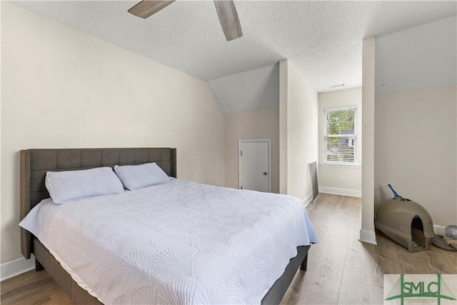 90 Cottage Ct, Richmond Hill, GA 31324 - bedroom featuring baseboards, a textured ceiling, wood finished floors, and vaulted ceiling