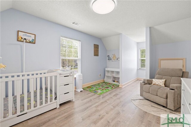 90 Cottage Ct, Richmond Hill, GA 31324 - bedroom with a textured ceiling, visible vents, vaulted ceiling, and light wood-type flooring