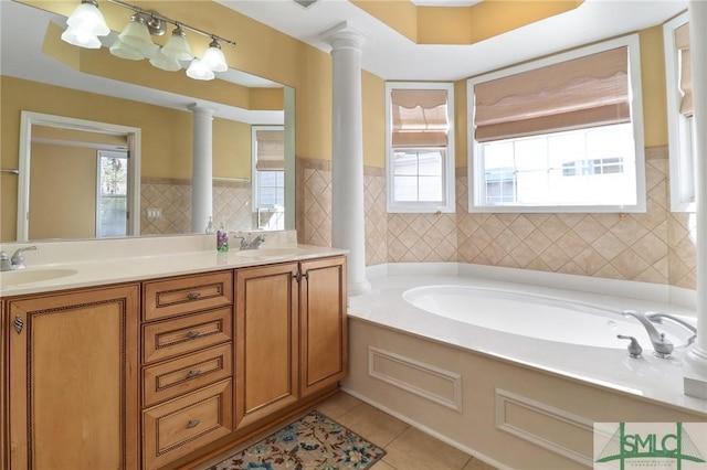 bathroom with ornate columns, a sink, tile patterned floors, and a bath