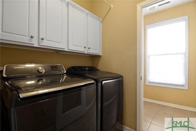 laundry area featuring light tile patterned floors, cabinet space, baseboards, and separate washer and dryer