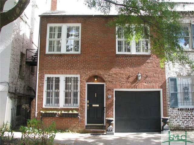 view of front of property featuring brick siding, a garage, and a chimney