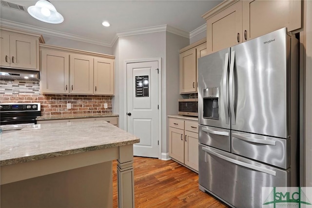 kitchen featuring cream cabinets, stainless steel appliances, under cabinet range hood, and visible vents