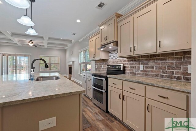 kitchen featuring double oven range, under cabinet range hood, decorative backsplash, a sink, and visible vents