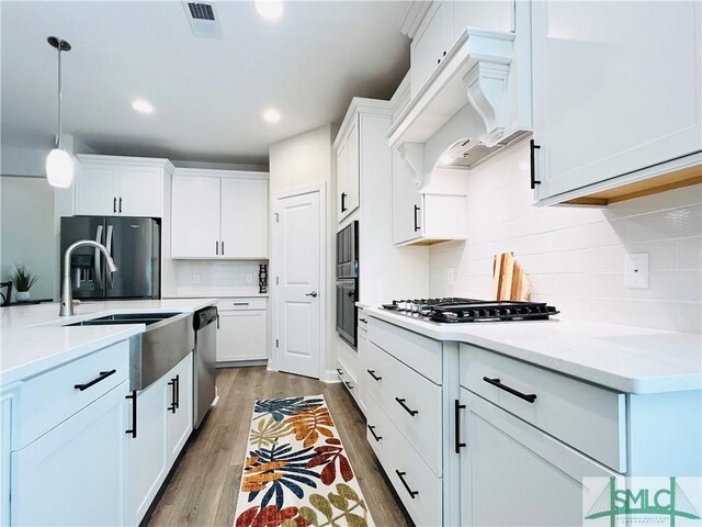 125 Long Creek Ln, Richmond Hill, GA 31324 - kitchen with premium range hood, stainless steel appliances, wood finished floors, light countertops, and backsplash