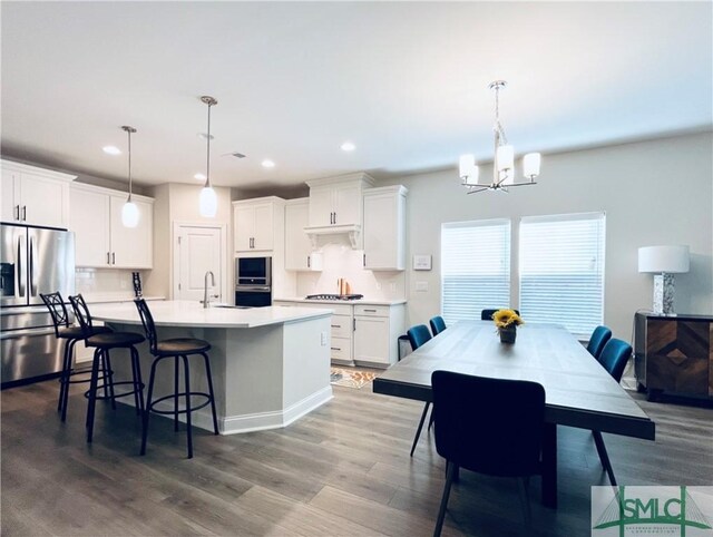 125 Long Creek Ln, Richmond Hill, GA 31324 - kitchen featuring stainless steel refrigerator with ice dispenser, a chandelier, dark wood-style flooring, light countertops, and a center island with sink