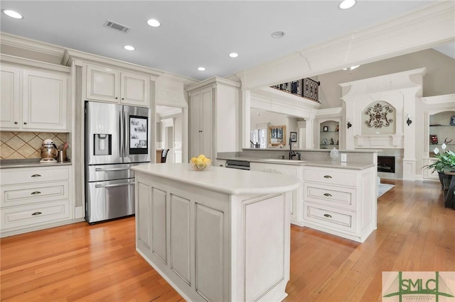 kitchen featuring stainless steel fridge with ice dispenser, visible vents, light wood-style floors, and a sink