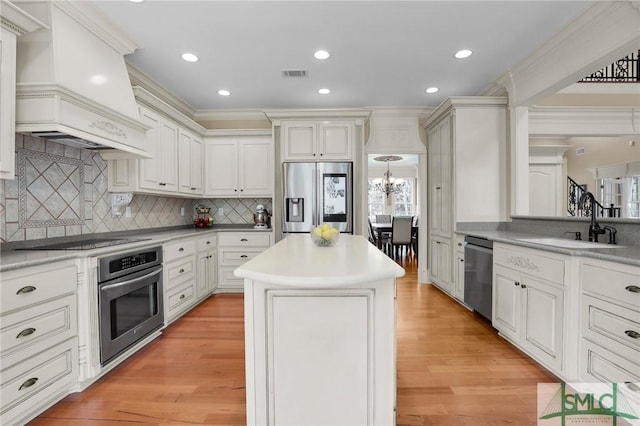 kitchen with light wood-style flooring, visible vents, appliances with stainless steel finishes, custom range hood, and a center island