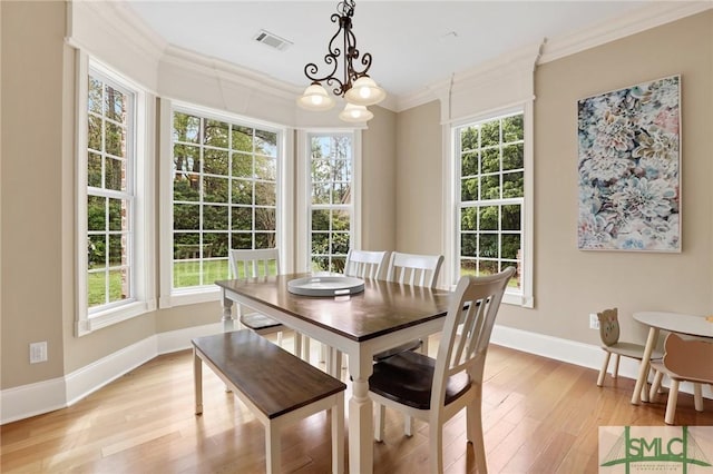 dining area with crown molding, light wood finished floors, baseboards, visible vents, and an inviting chandelier