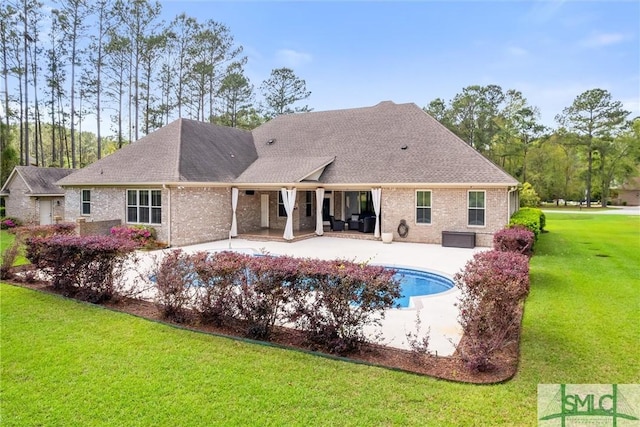 back of house featuring a yard, a patio area, and brick siding