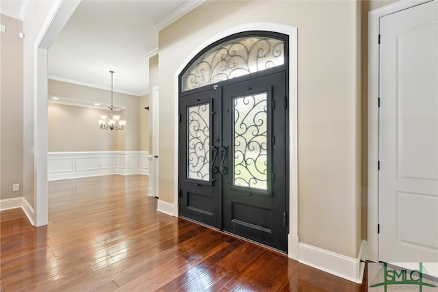 foyer featuring french doors, ornamental molding, an inviting chandelier, and hardwood / wood-style floors