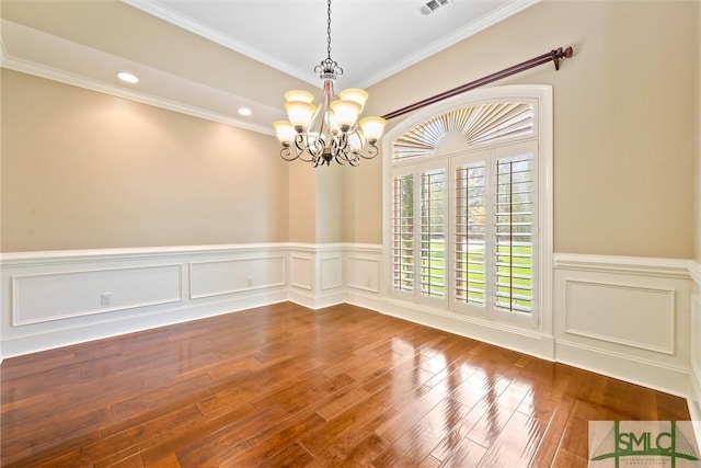 unfurnished dining area featuring a wainscoted wall, a chandelier, and wood finished floors