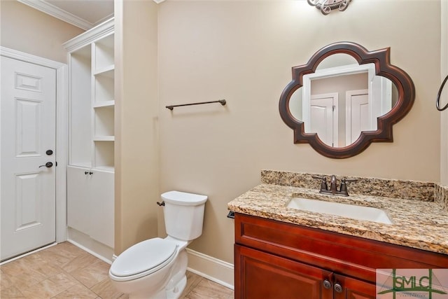 bathroom with vanity, baseboards, ornamental molding, and toilet