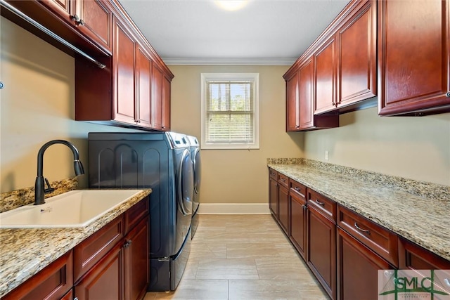 laundry area with ornamental molding, a sink, washer and dryer, baseboards, and cabinet space