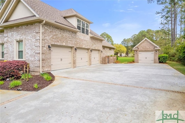 view of side of home with brick siding, an attached garage, a shingled roof, and concrete driveway