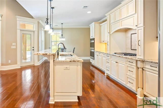 kitchen featuring crown molding, visible vents, appliances with stainless steel finishes, a sink, and a center island with sink