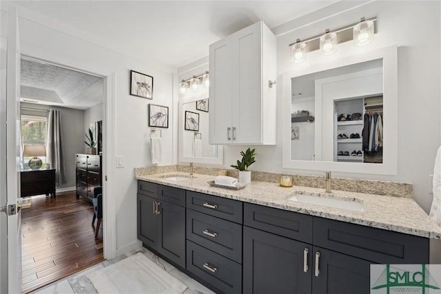 bathroom featuring double vanity, a sink, ensuite bathroom, and baseboards