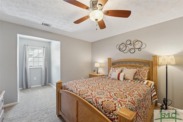 bedroom with baseboards, a textured ceiling, visible vents, and light carpet