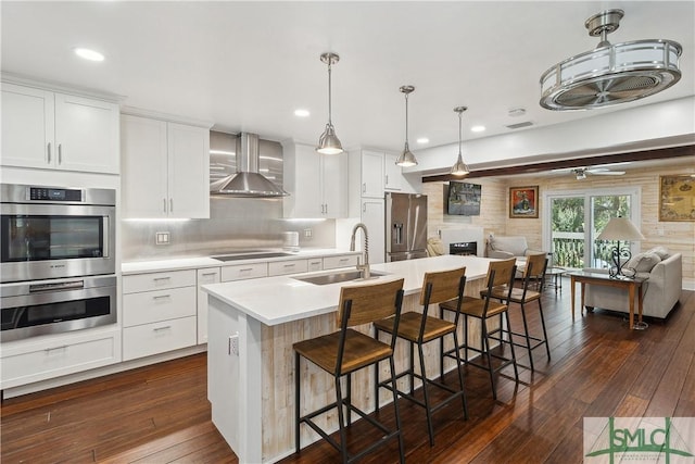 1000 Sea Island Rd Unit 56, Saint Simons Island, GA 31522 - kitchen with wall chimney range hood, stainless steel appliances, open floor plan, dark wood-type flooring, and light countertops