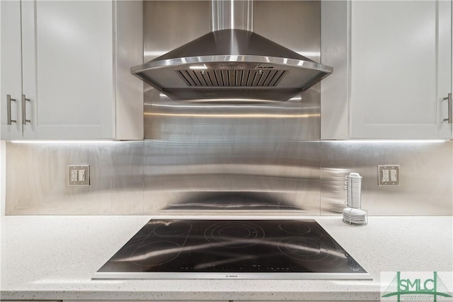 1000 Sea Island Rd Unit 56, Saint Simons Island, GA 31522 - kitchen view of wall chimney exhaust hood, black electric stovetop, backsplash, and white cabinetry