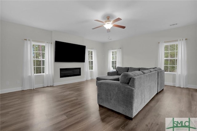 living area with baseboards, visible vents, ceiling fan, and wood finished floors