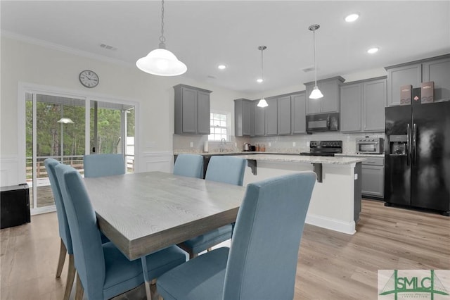 dining room with recessed lighting, ornamental molding, a wainscoted wall, light wood finished floors, and visible vents