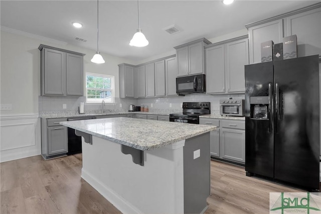 kitchen with tasteful backsplash, a center island, gray cabinetry, visible vents, and black appliances