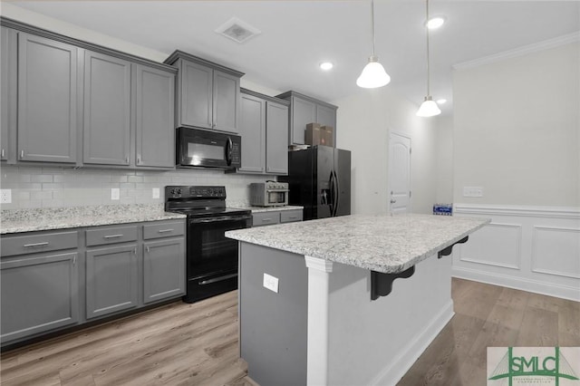 kitchen featuring tasteful backsplash, gray cabinets, a center island, light wood-style floors, and black appliances