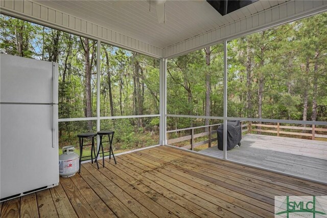 unfurnished sunroom featuring a healthy amount of sunlight and ceiling fan
