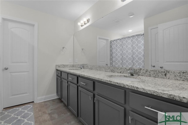 bathroom featuring double vanity, baseboards, and a sink