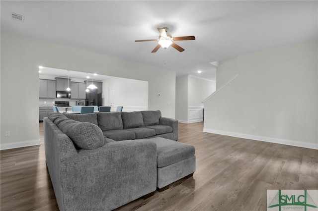 living room with visible vents, dark wood-type flooring, baseboards, and ceiling fan