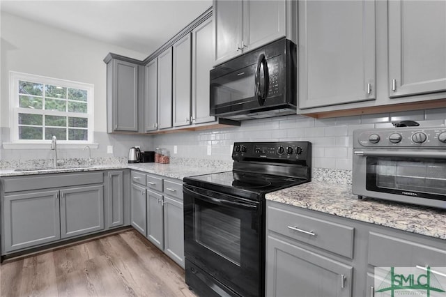 kitchen with gray cabinets, a sink, and black appliances
