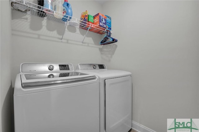 clothes washing area featuring baseboards, laundry area, and washer and clothes dryer